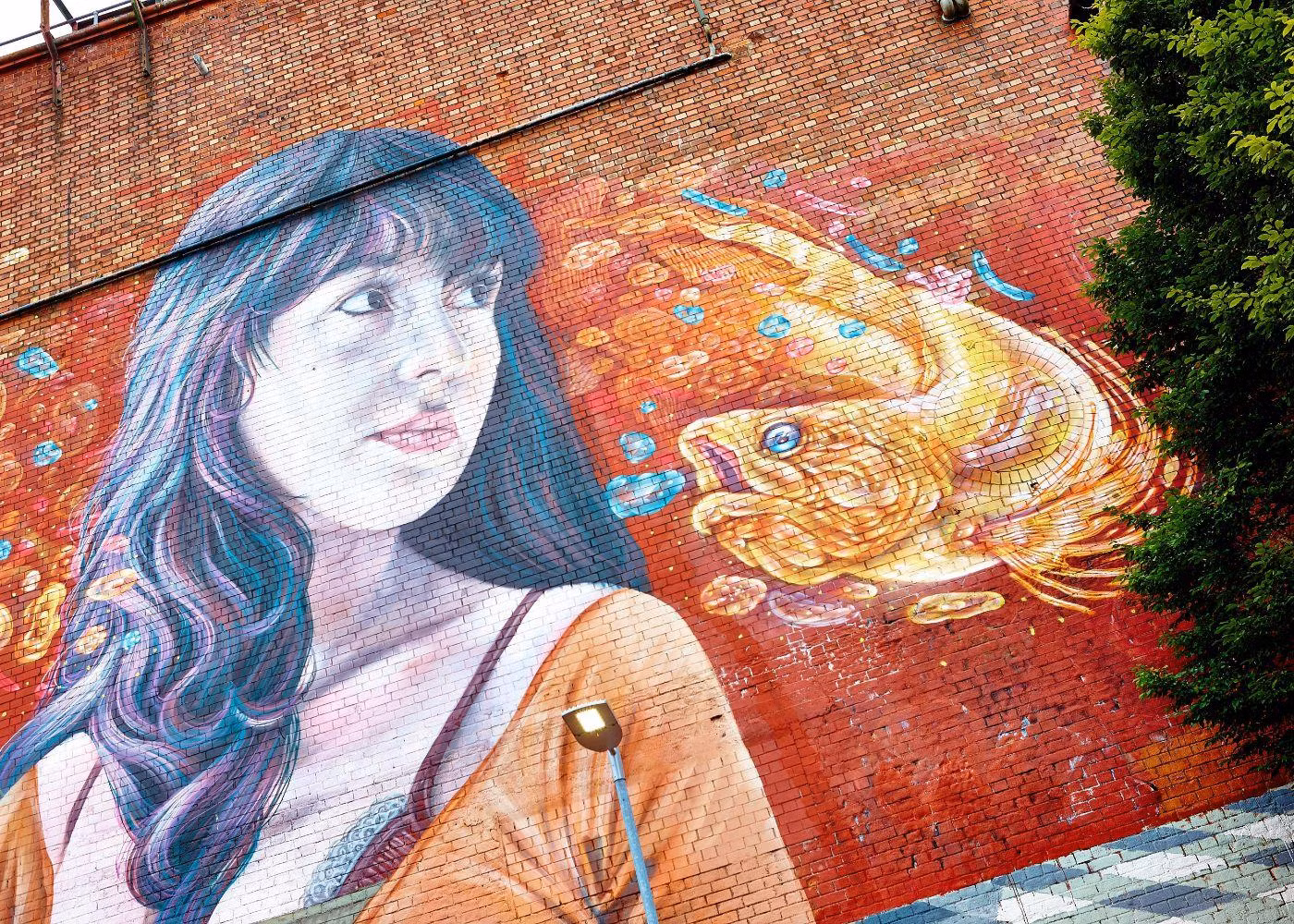 A Wall Painting in Bradley Stoke With a Woman and Fish With a Focused Expression as She Gazes at Her Surroundings
