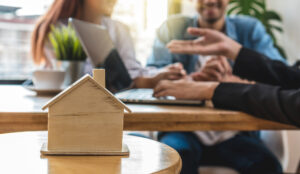 A man and woman sit at a table examining a house model.
