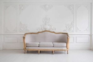 White couch positioned before a wall featuring intricate carvings.