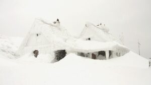 Snow-covered house on a hillside, surrounded by a winter landscape.