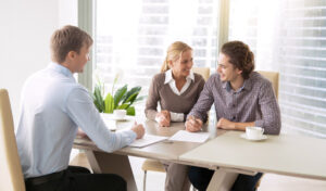 Three individuals seated at a table with papers and coffee.