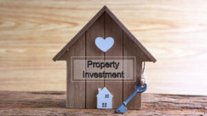 Wooden house model with a key, symbolising property investment.
