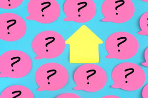 Question mark on pink paper against a blue background of question marks.