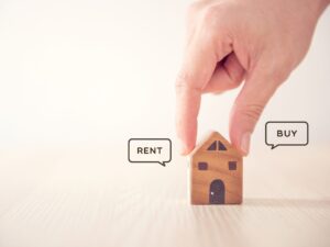 a hand is placing a house in the middle of a table