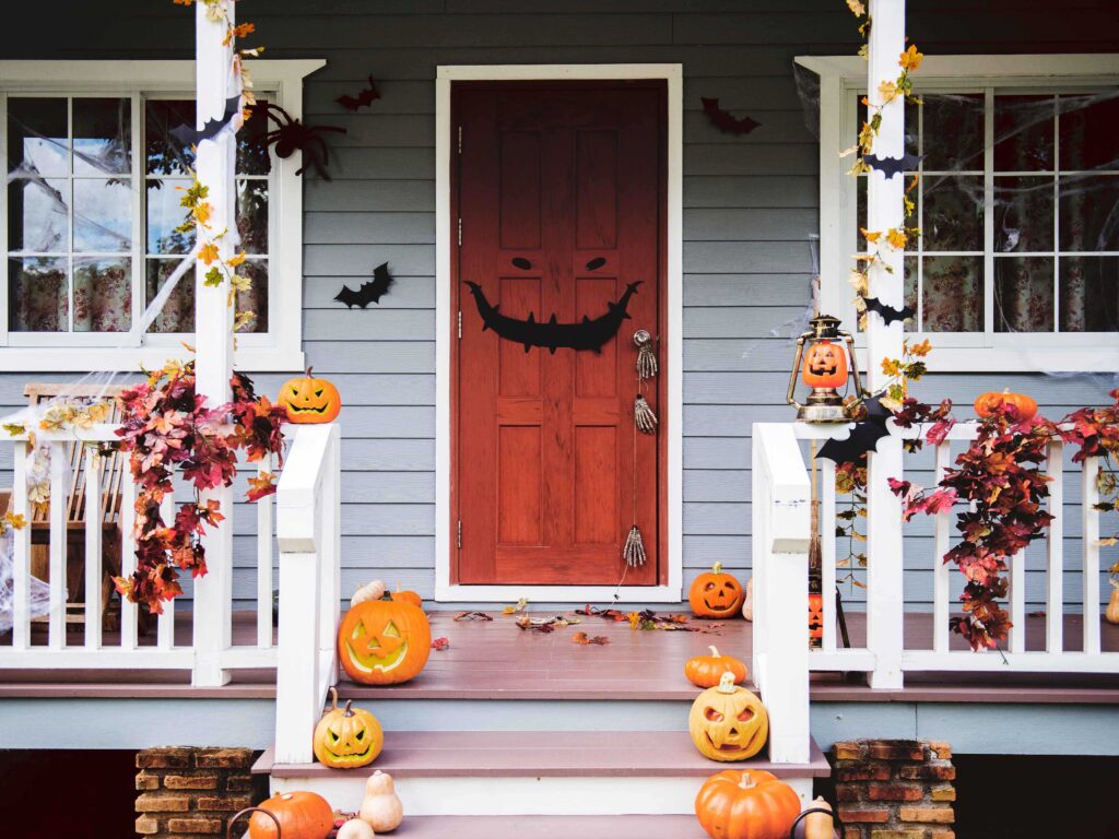 Halloween decorations adorn a porch with pumpkins and cobwebs.