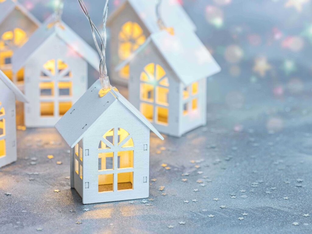 Small illuminated paper houses on a shimmering silver background.