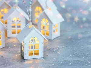 Small illuminated paper houses on a shimmering silver background.