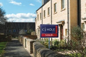 Sold sign displayed in front of a row of residential houses.