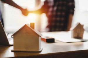 Real estate agent shaking hands with a miniature house model.