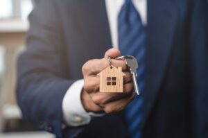 A man in a suit holds a key, symbolising home ownership.