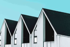 Three houses featuring black roofs and white windows.