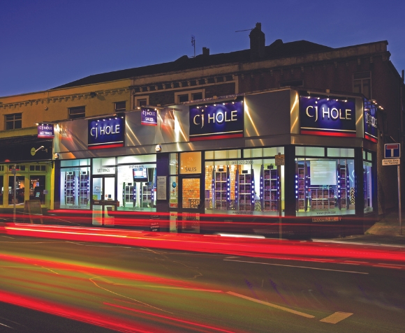 CJ Hole estate agent office storefront featuring a red and blue sign prominently displayed.