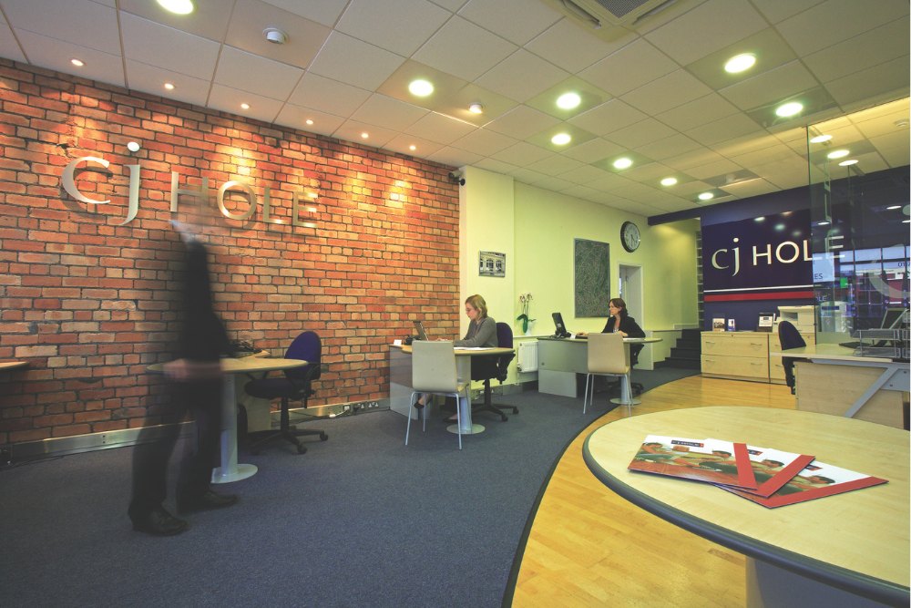 One of the CJ Hole estate agent offices featuring a brick wall and a sleek table.