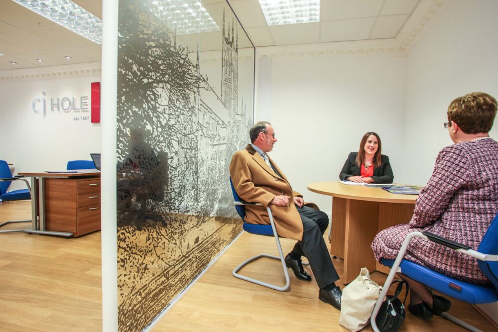 A landlord speaking with an estate agent inside a CJ Hole branch office