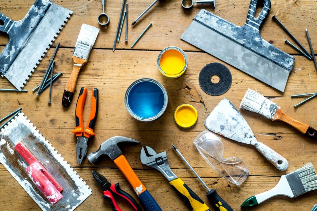 Tools and paint supplies arranged on a wooden table.