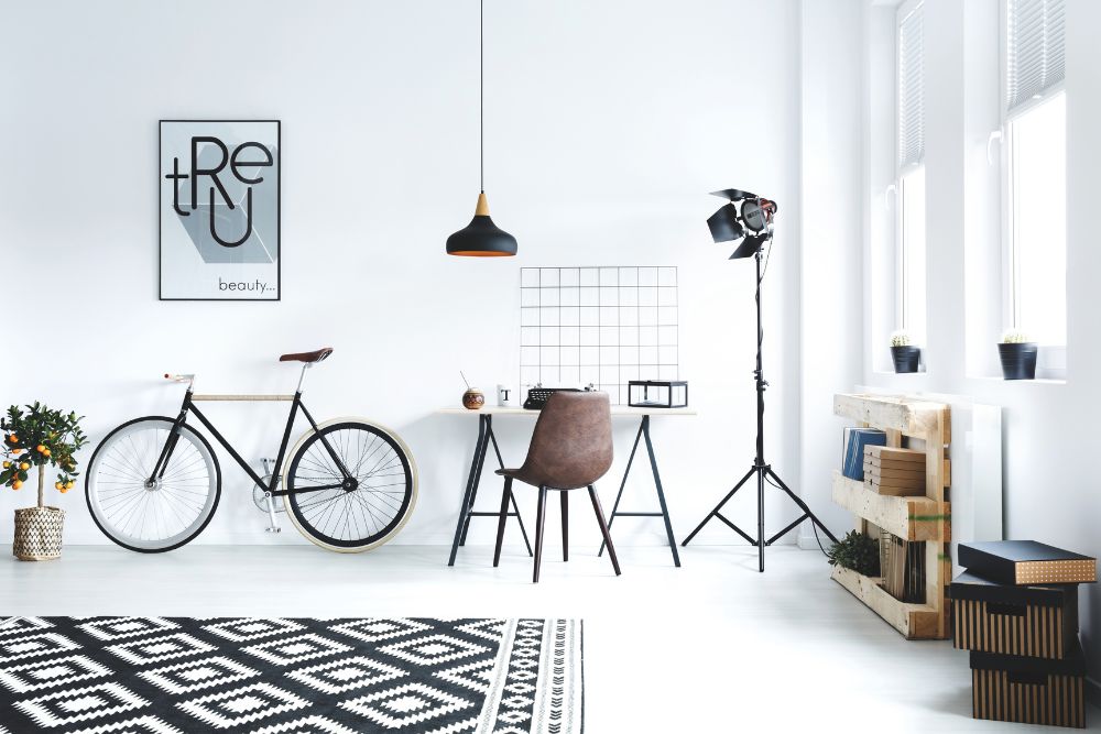 A white room featuring a bicycle, desk, and chair.