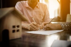Man and woman signing a contract for their new house purchase.