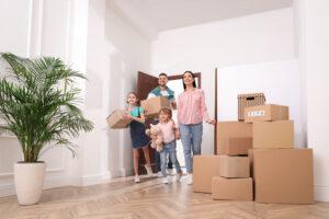 Family carrying boxes while moving into a new home together.