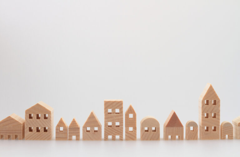Wooden toy houses arranged on a white background.