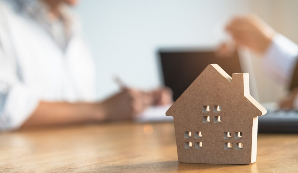 House model on a table beside a laptop, showcasing design ideas.
