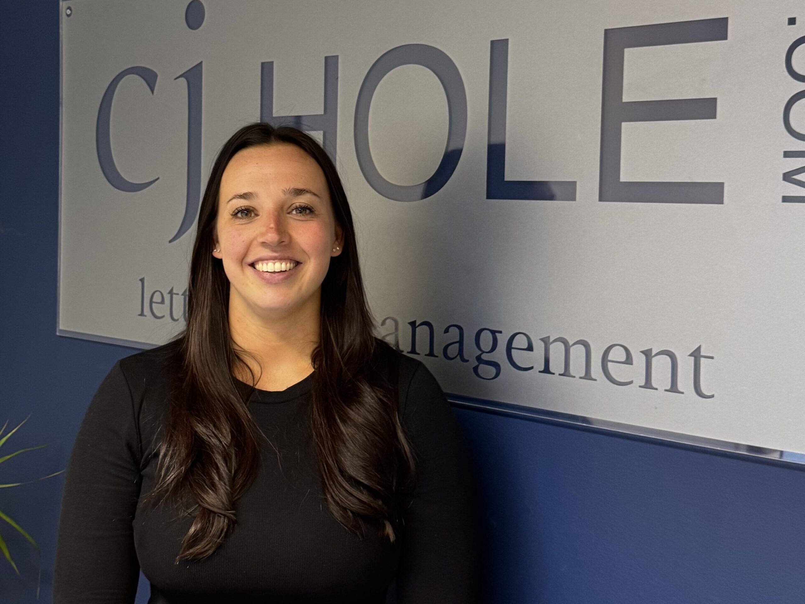 A property consultant posing inside the CJ Hole Quedgeley estate agent office.