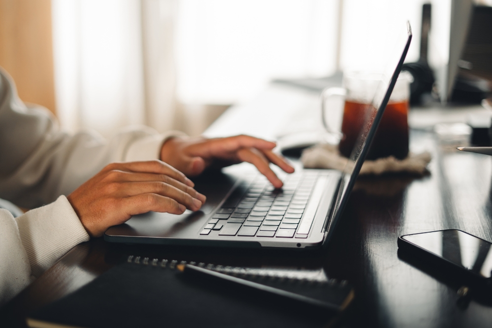 A student typing on a laptop computer at a desk.