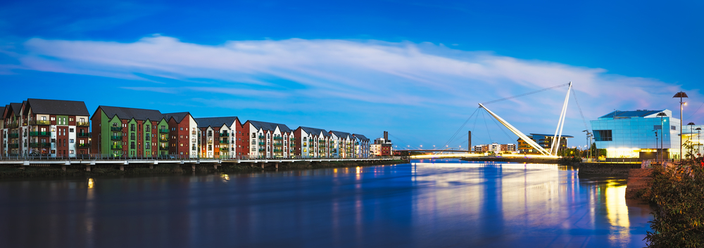 River flanked by buildings, featuring a bridge spanning across it.