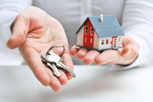 a person holding a house and keys