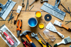 Tools and paint supplies arranged on a wooden table.
