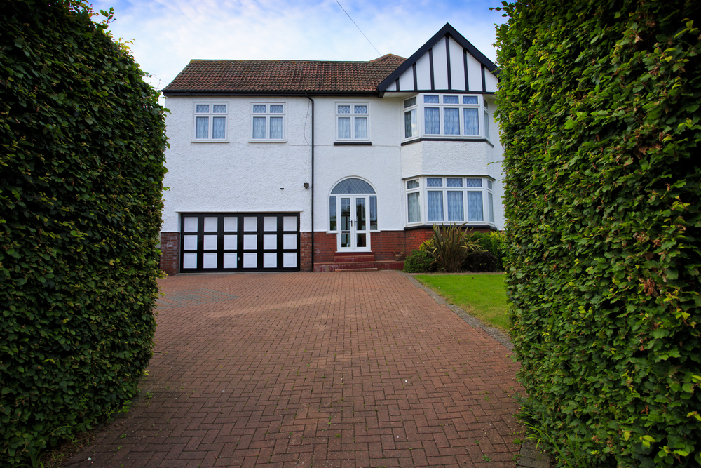 Large house surrounded by hedges with a spacious driveway.