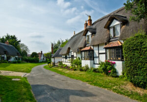 Thatched cottages nestled in serene countryside landscape.