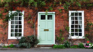 Green door and window on a brick house facade.