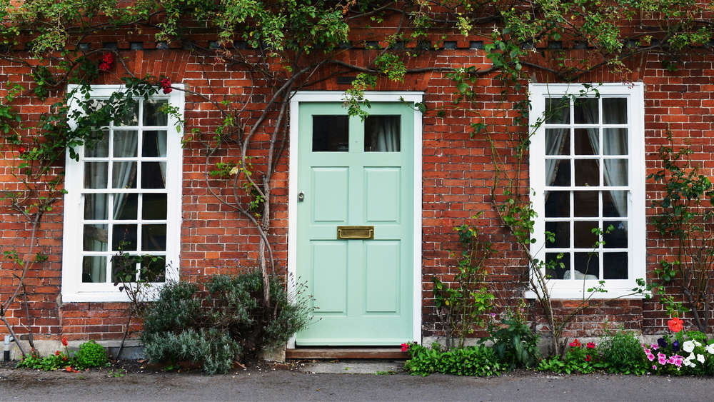 Green door and window on a brick house facade.