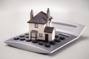 House model placed on a calculator, symbolising financial planning.