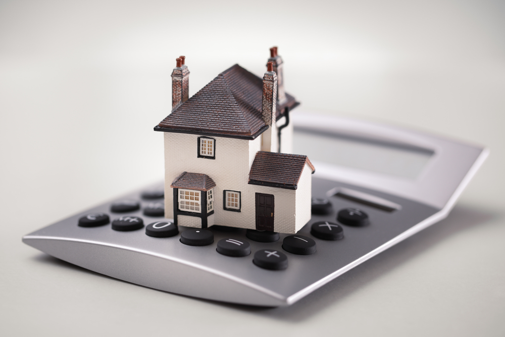 House model placed on a calculator, symbolising financial planning.
