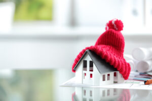 A house wearing a red hat beside a small model of a house.