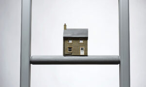 A miniature house perched on a ladder, creating a whimsical and imaginative scene.