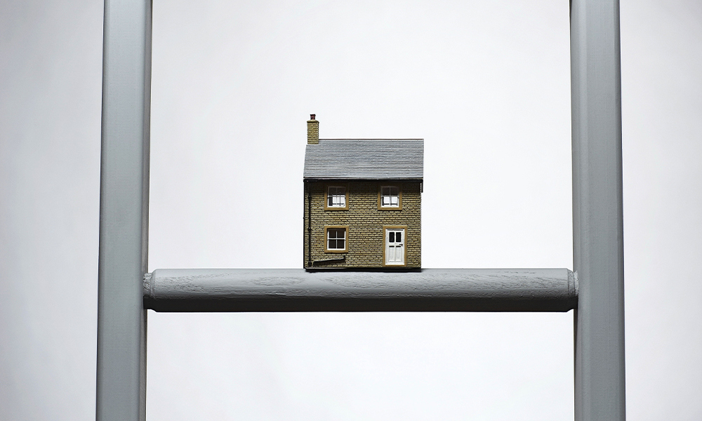 A miniature house perched on a ladder, creating a whimsical and imaginative scene.