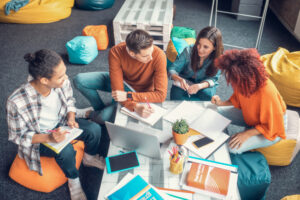 Four individuals seated on bean bags in a modern office setting.
