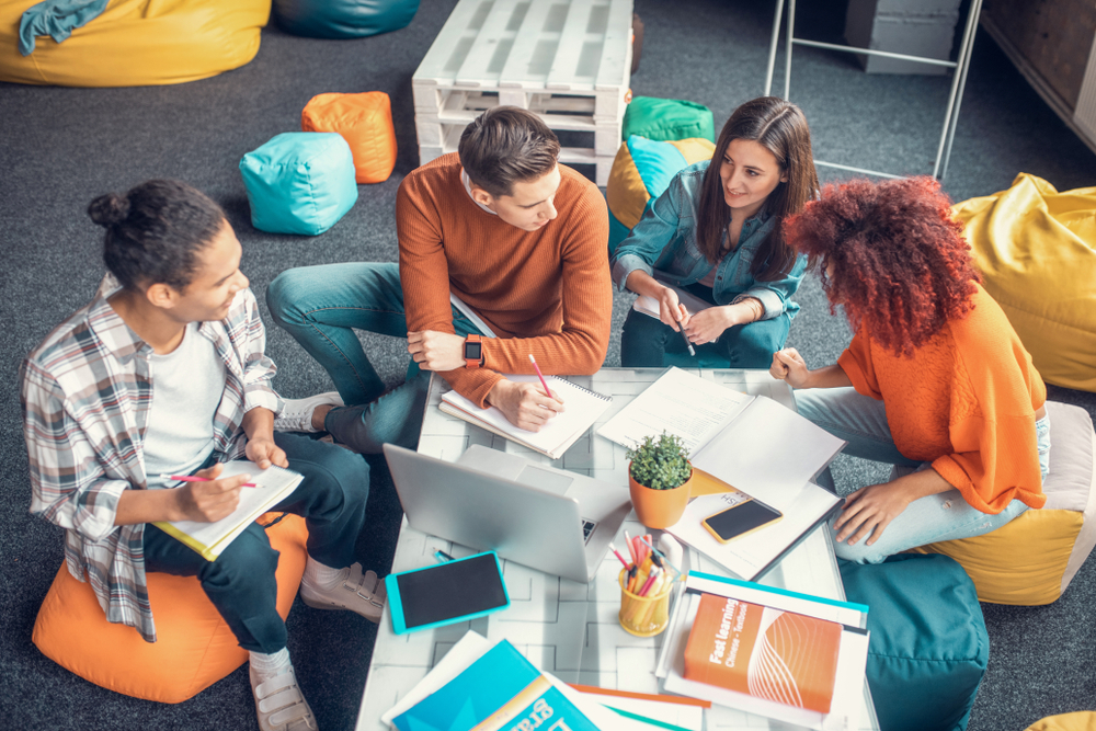 Four individuals seated on bean bags in a modern office setting.