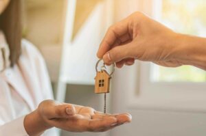 A woman hands a key to a man, both holding house keys.