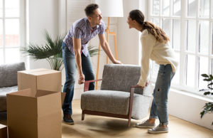 a man and woman moving boxes in a living room