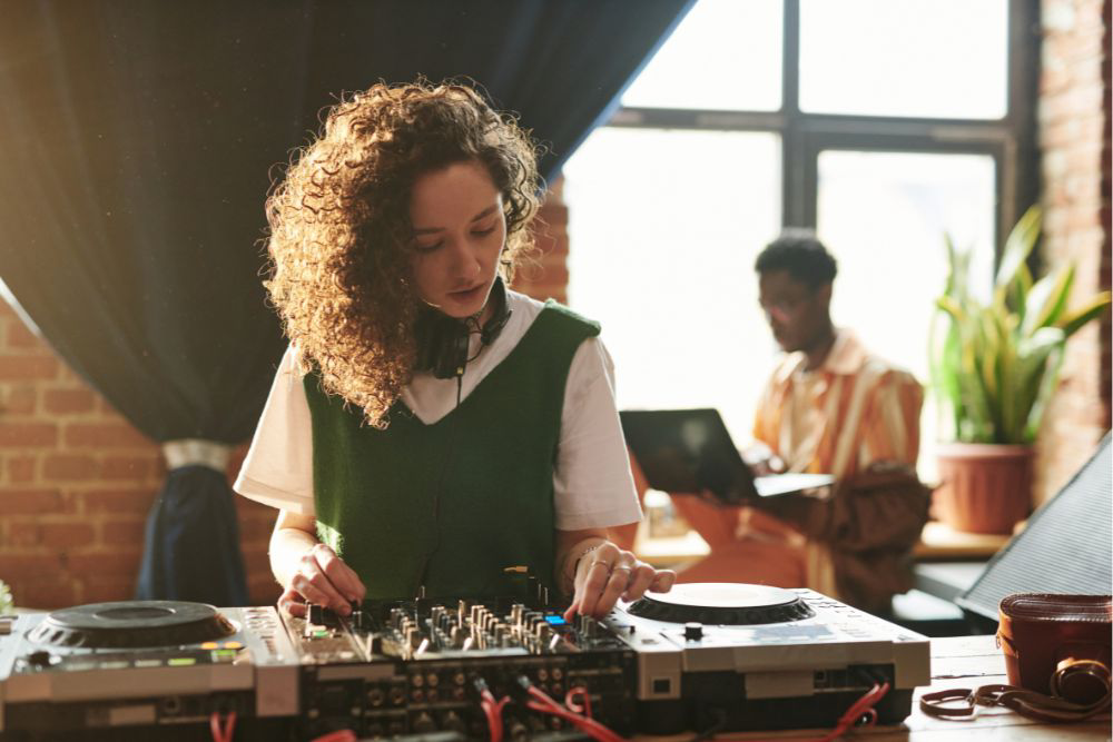 A student skillfully mixes music on a DJ mixer at an event